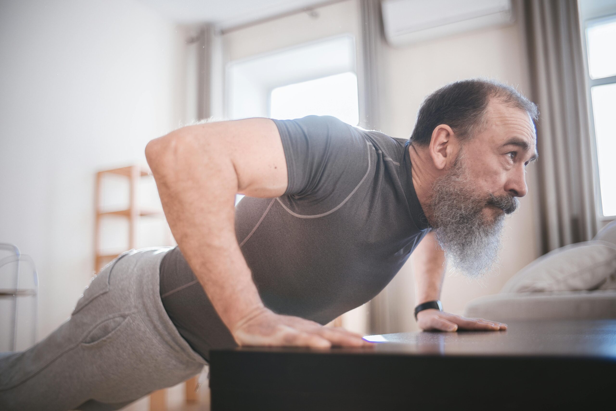 Older Athletes Elderly man performing push-ups in his living room for fitness and health.